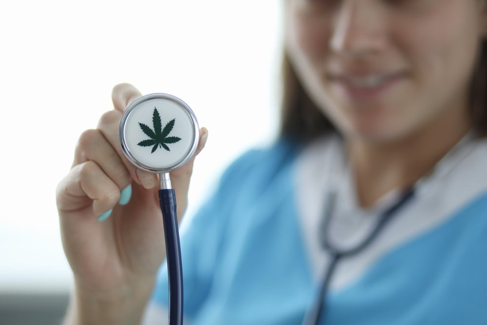 female doctor holding stethoscope with marijuana leaf