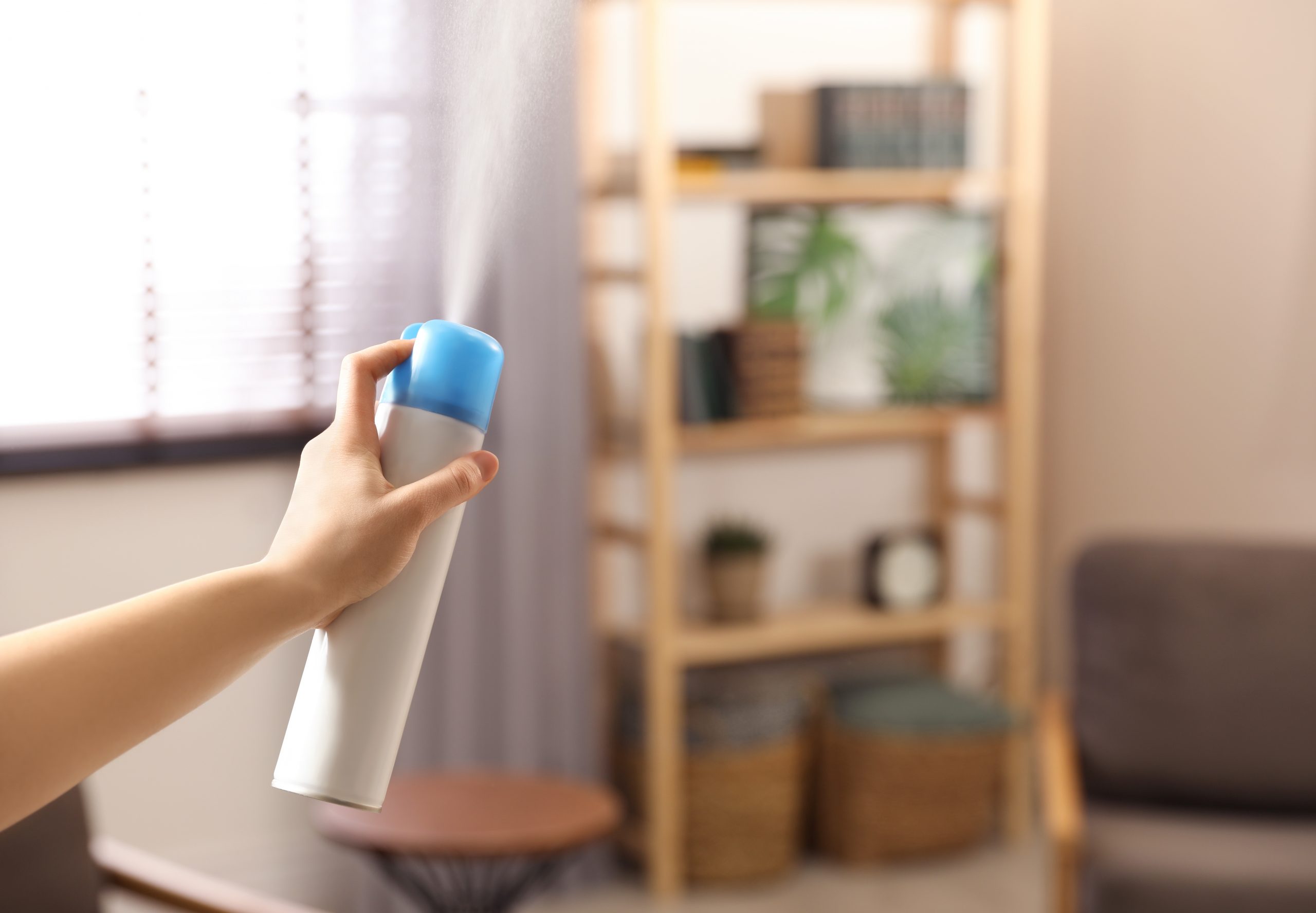 person spraying air freshener in a room