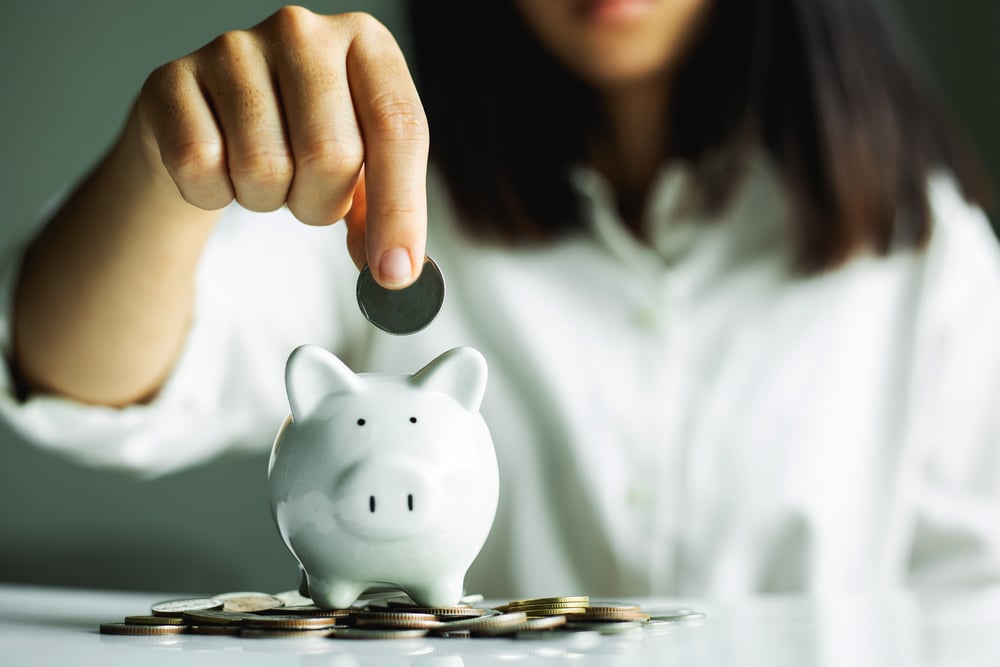 woman adding money to a piggy bank